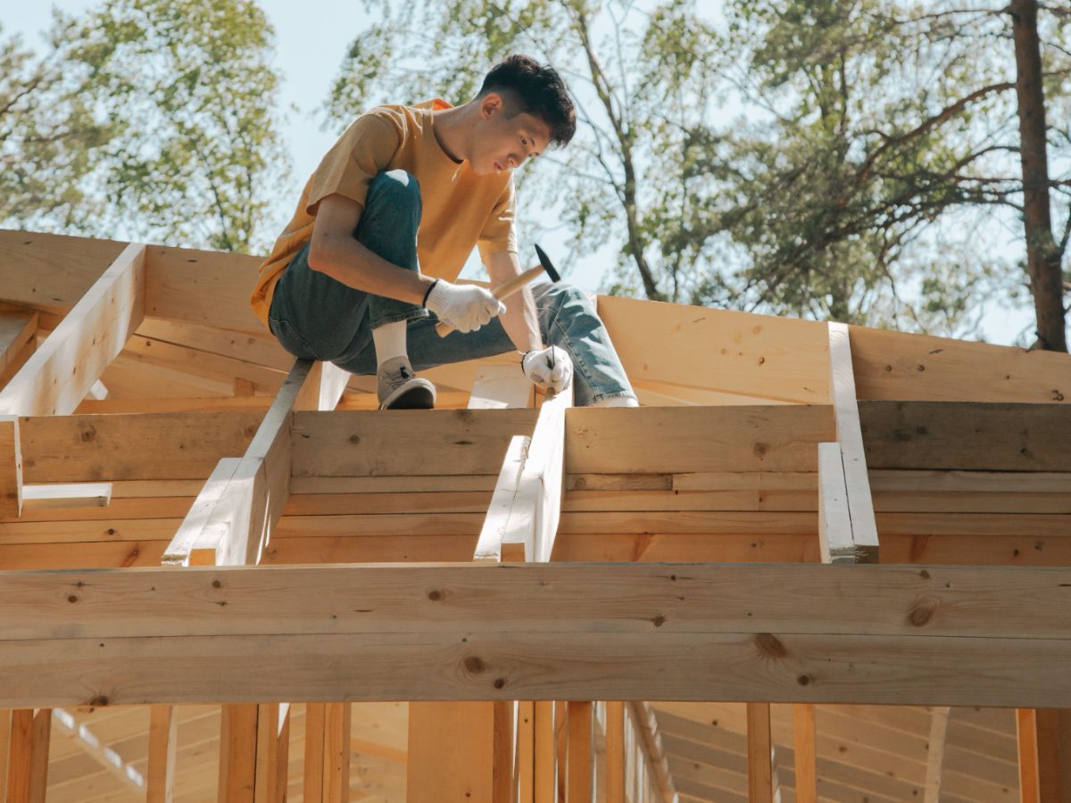 Carpenter hammering on the roof structure of a house under construction: the soundness of the shell, covered for ten years by ten-year liability insurance
